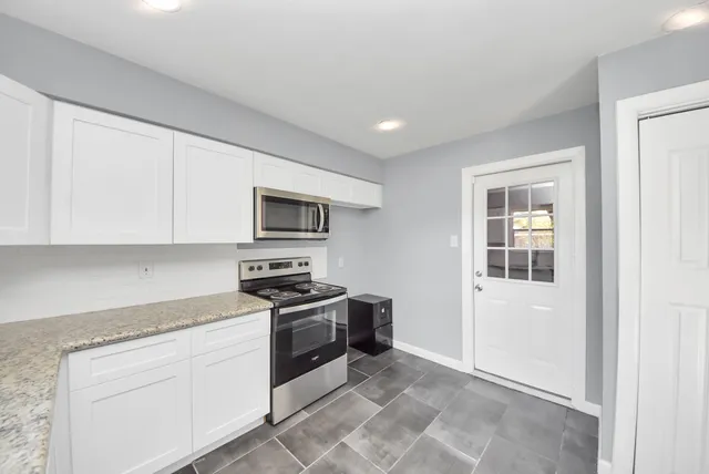 a kitchen with granite countertop white cabinets and stainless steel appliances