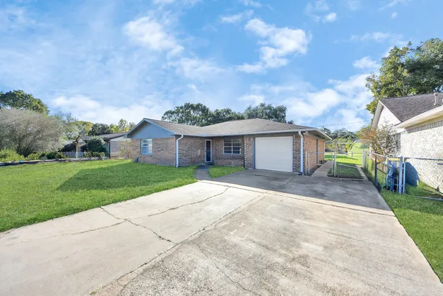 a view of a house with a yard and large tree