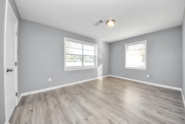 an empty room with wooden floor and windows