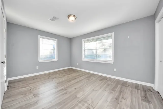 an empty room with wooden floor and windows