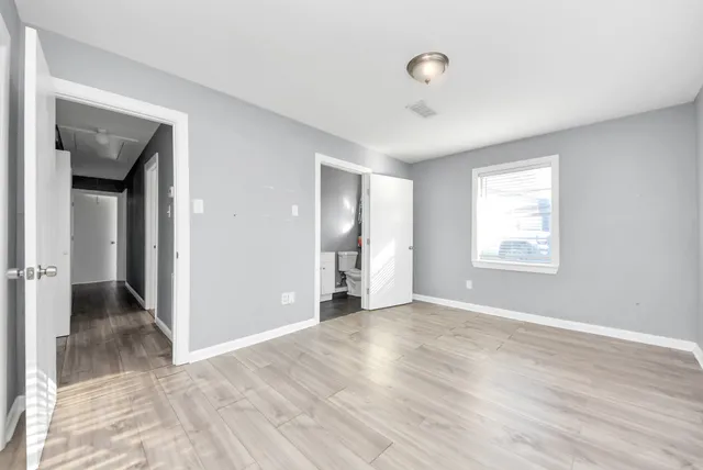 a view of an empty room with wooden floor and a window