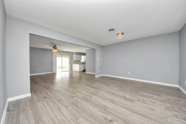 a view of an empty room with window and wooden floor