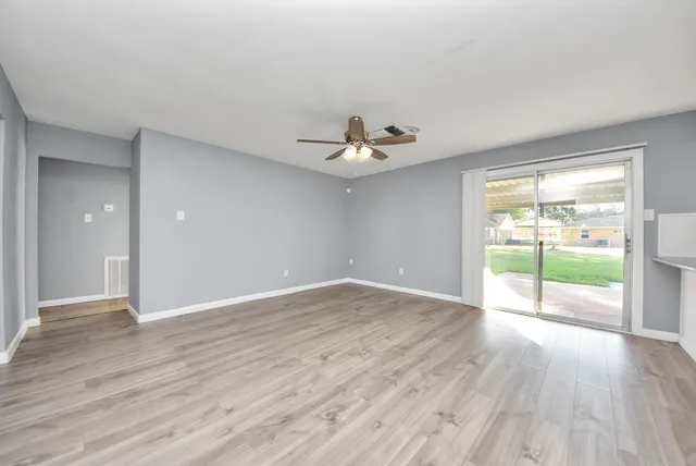 a view of an empty room with wooden floor and a window