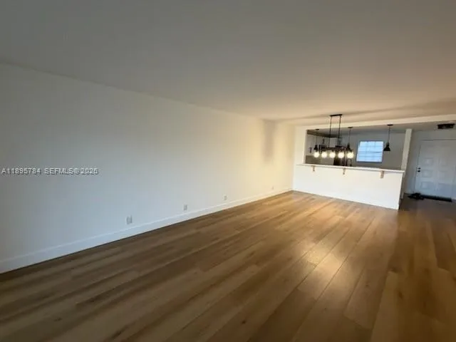 a view of empty room with wooden floor and window