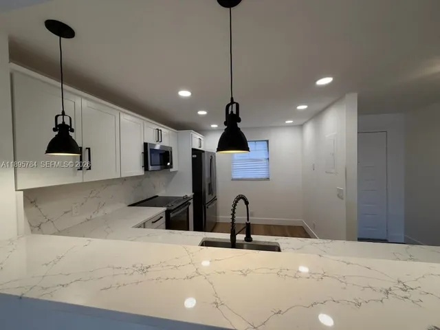 a kitchen with stainless steel appliances granite countertop a sink a stove and a refrigerator