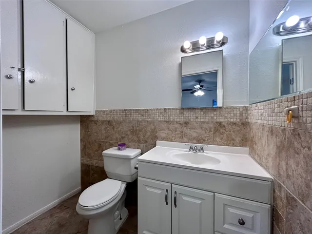 a bathroom with a toilet sink vanity and mirror