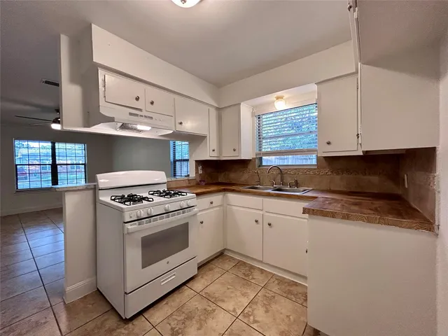 a kitchen with a sink appliances cabinets and a window