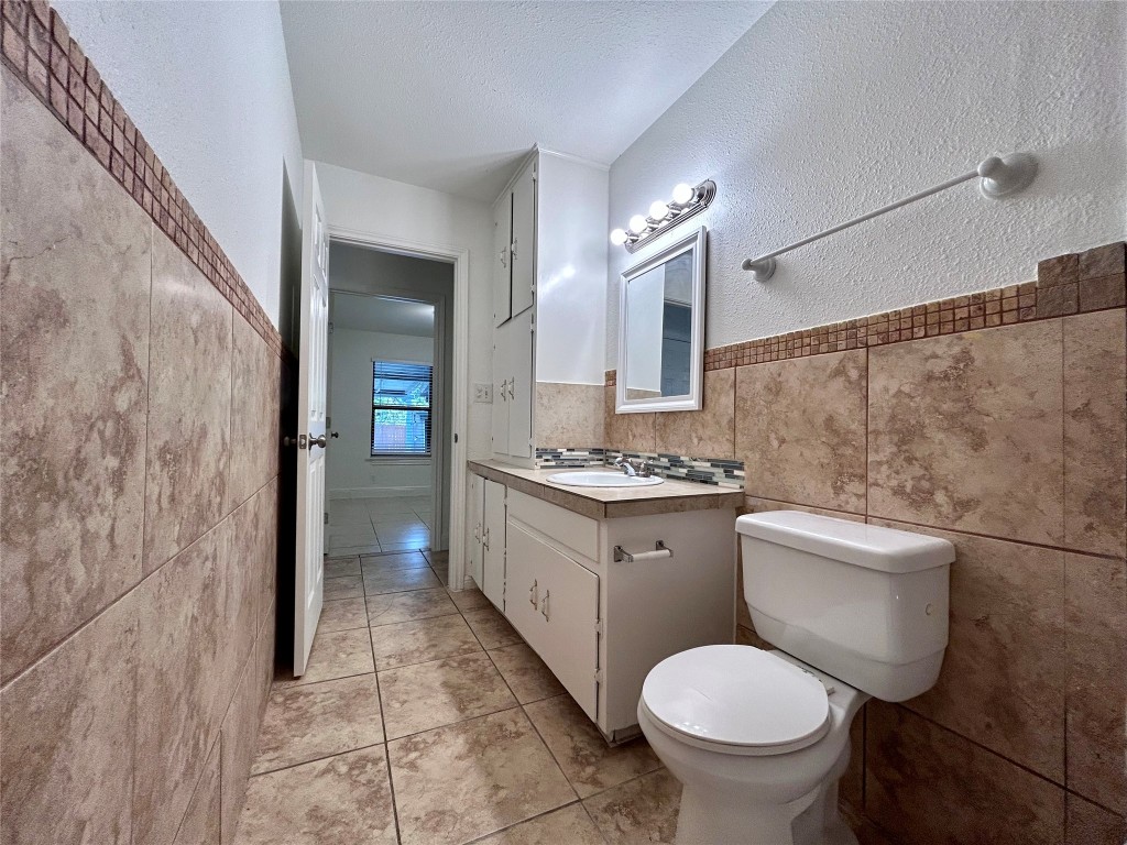 6200 Palm Circle Austin, TX 78741 - Photo 9 of 18 a bathroom with a granite countertop toilet a sink and a mirror