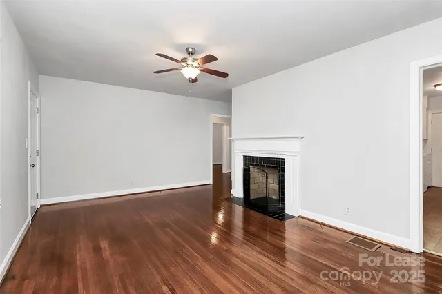 a view of an empty room with wooden floor and a fireplace