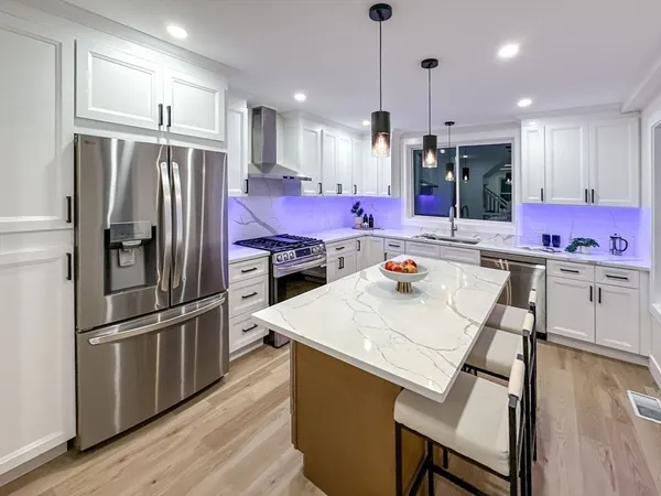 a kitchen with kitchen island a stove a sink a refrigerator and chairs
