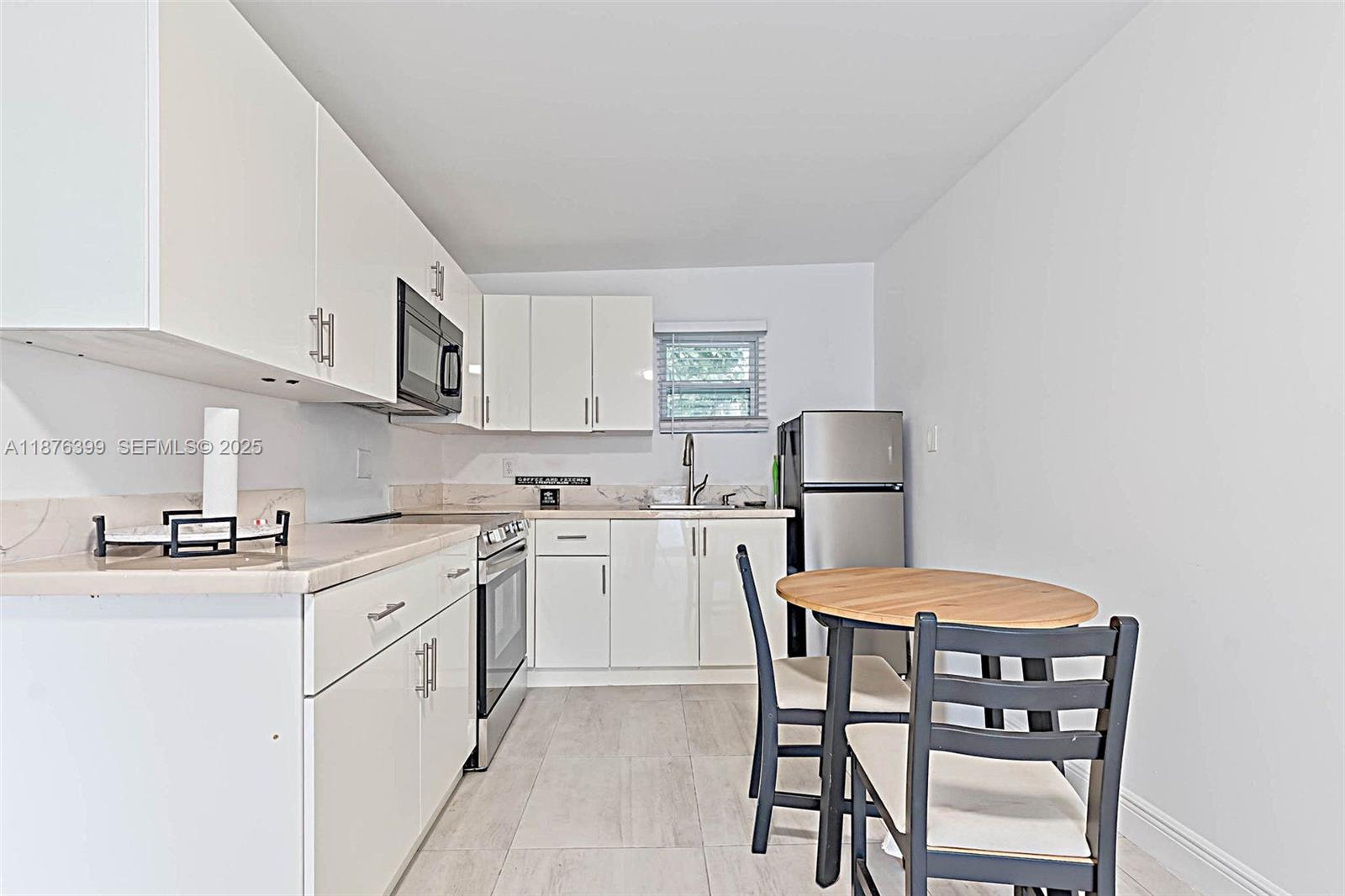 259 Northeast 56th Street, Unit 2 Miami, FL 33137 - Photo 7 of 23 a kitchen with a stove a sink and white cabinets