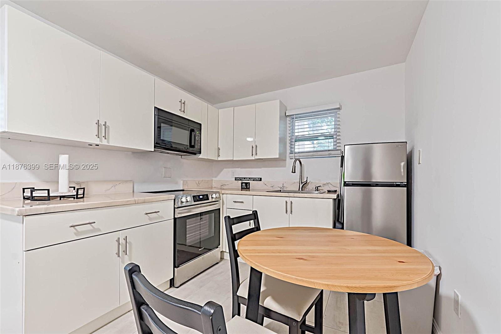 259 Northeast 56th Street, Unit 2 Miami, FL 33137 - Photo 8 of 23 a kitchen with stainless steel appliances white cabinets and wooden floor