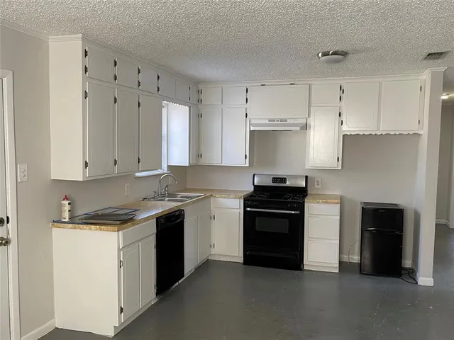a kitchen with granite countertop white cabinets and black stainless steel appliances
