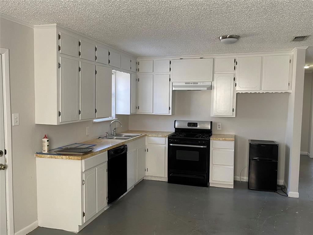 117 East Prospect Street Denison, TX 75021 - Photo 6 of 13 a kitchen with granite countertop white cabinets and black stainless steel appliances