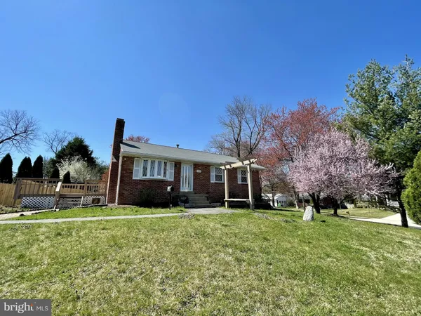 a view of house in front of a big yard with large trees