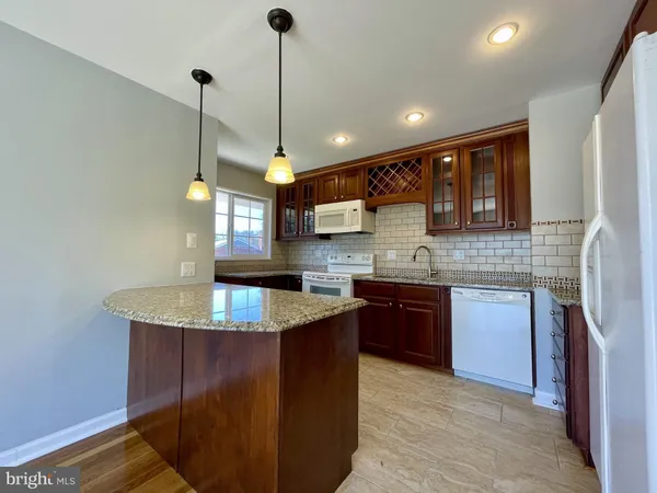 a kitchen with kitchen island granite countertop a sink a counter space appliances and cabinets