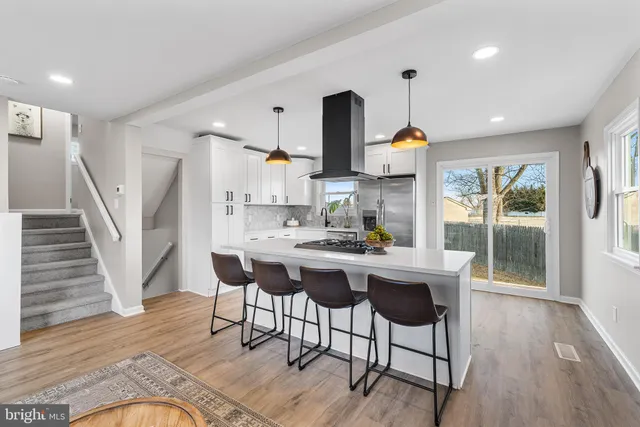 a kitchen with stainless steel appliances a dining table chairs and wooden floor