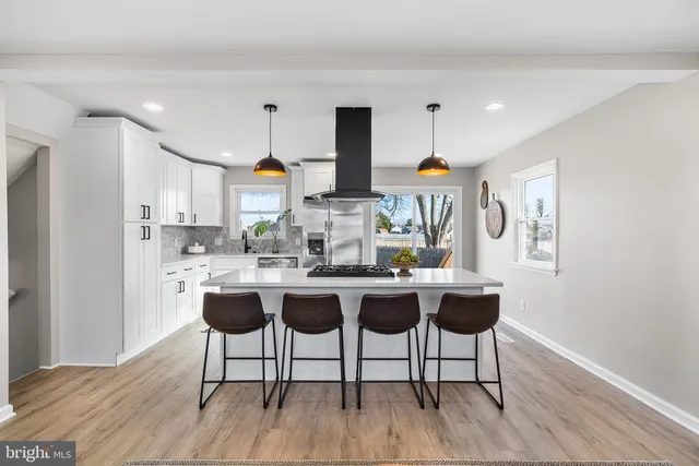 a kitchen with stainless steel appliances granite countertop a table chairs and a refrigerator
