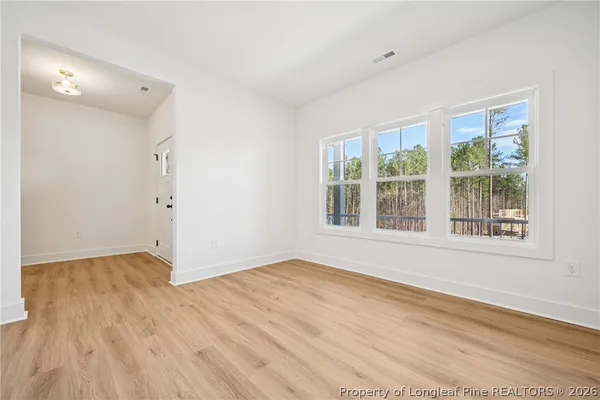 an empty room with wooden floor fireplace and windows