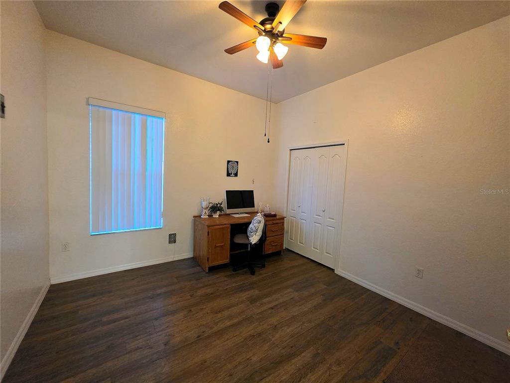 2116 Northeast 40th Terrace Ocala, FL 34470 - Photo 17 of 37 a view of a room with wooden floor a ceiling fan and windows