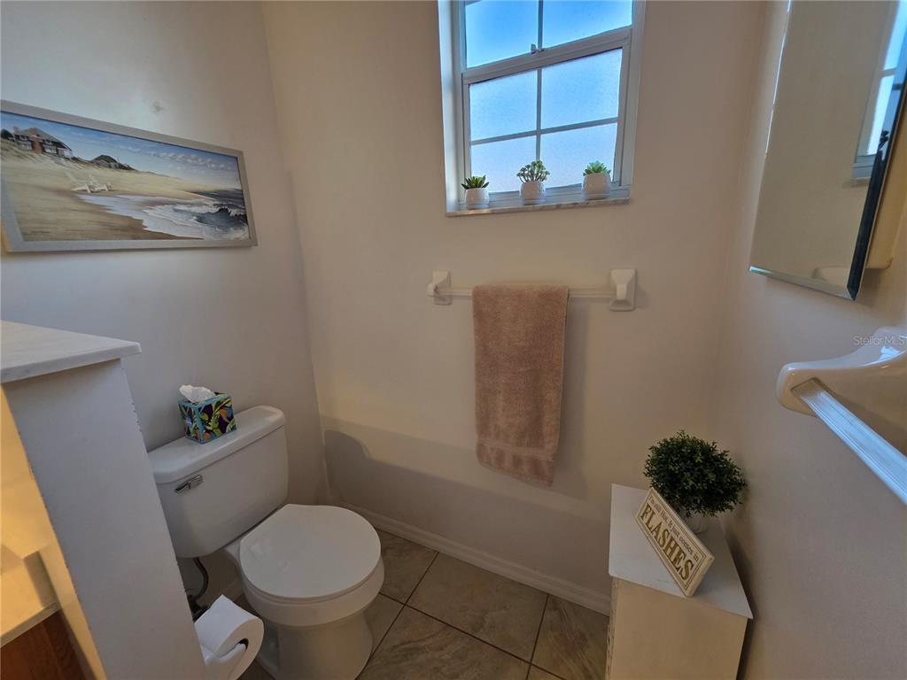 2116 Northeast 40th Terrace Ocala, FL 34470 - Photo 24 of 37 a white toilet sitting next to a bathroom sink and a mirror