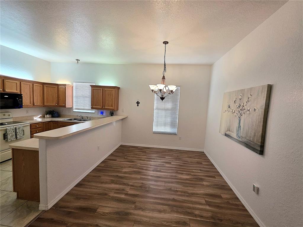 2116 Northeast 40th Terrace Ocala, FL 34470 - Photo 3 of 37 a kitchen with stainless steel appliances granite countertop a refrigerator a stove oven a sink dishwasher and white cabinets with wooden floor