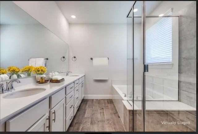 a large kitchen with granite countertop a stove a sink dishwasher a refrigerator and white cabinets with wooden floor