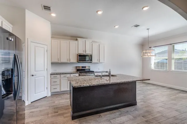 a kitchen with kitchen island granite countertop a stove a sink and a refrigerator