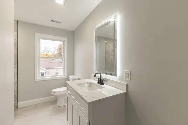 a bathroom with a sink toilet and window
