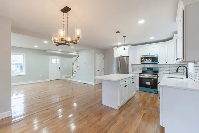 a large kitchen with stainless steel appliances granite countertop a stove a sink dishwasher and a oven with white cabinets