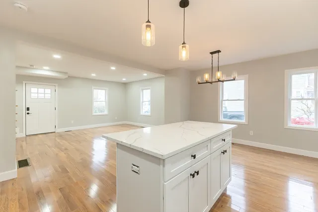 a kitchen with a sink chandelier and wooden floor