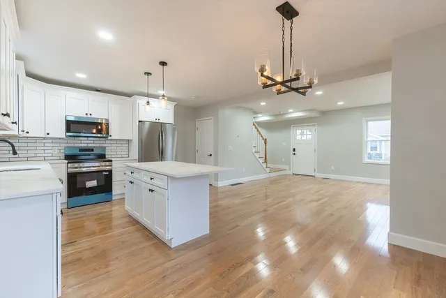 a kitchen with stainless steel appliances kitchen island granite countertop a stove top oven a sink a refrigerator and a granite counter tops