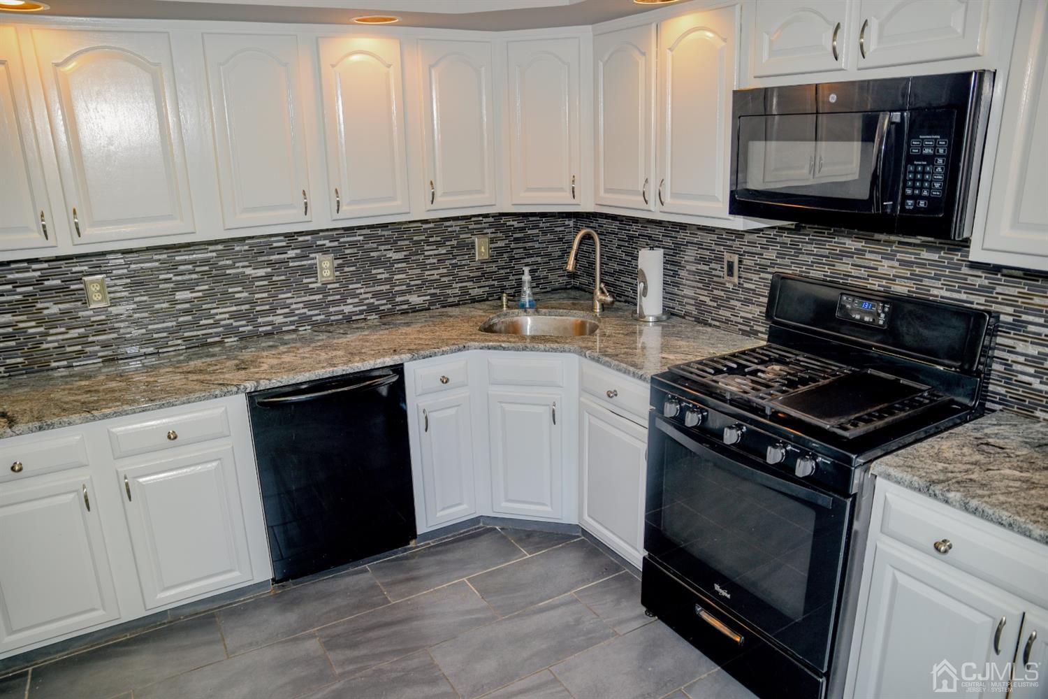 4206 Riddle Court Bridgewater, NJ 08807 - Photo 4 of 25 a kitchen with granite countertop a stove top oven microwave and cabinets