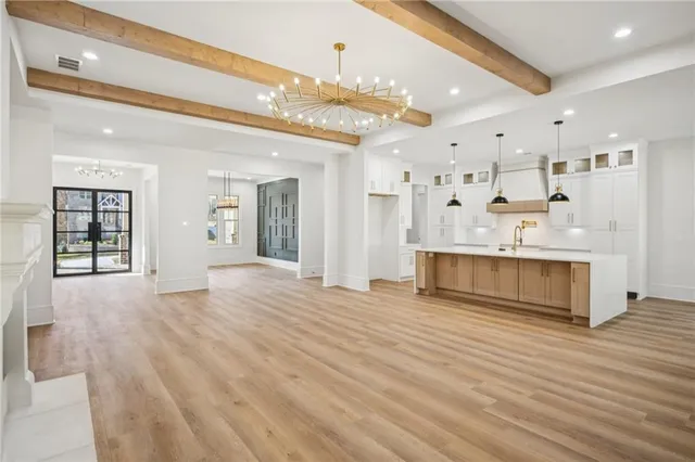 a large white kitchen with a stove a sink dishwasher and a refrigerator with wooden floor