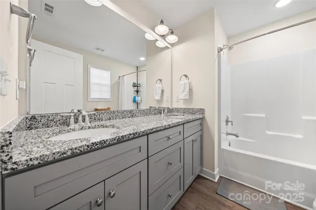 a bathroom with a granite countertop sink a large mirror and a bathtub