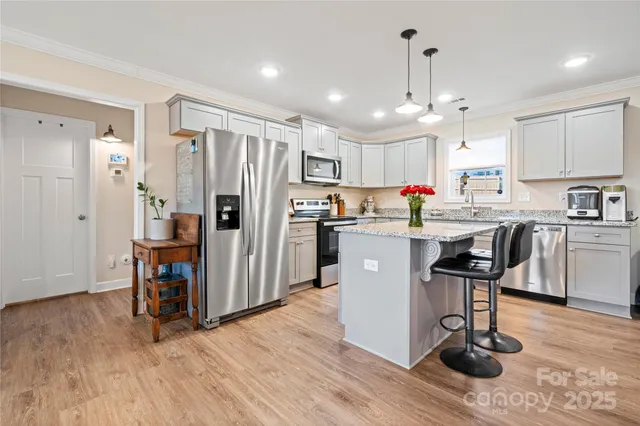 a kitchen with a sink a refrigerator and wooden floor