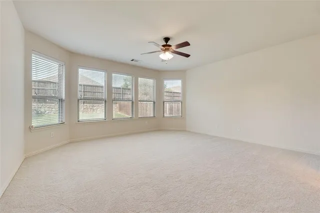 a view of empty room with wooden floor and ceiling fan