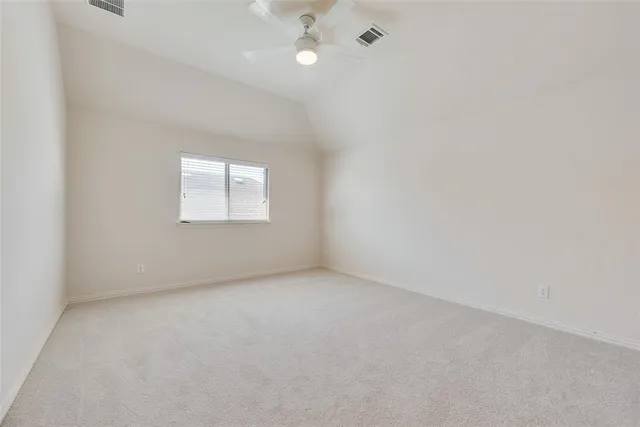 an empty room with chandelier fan and windows