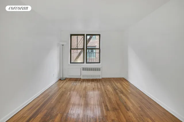 a view of an empty room with wooden floor and window