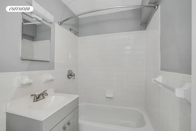 a white bath tub sitting next to a white sink and vanity