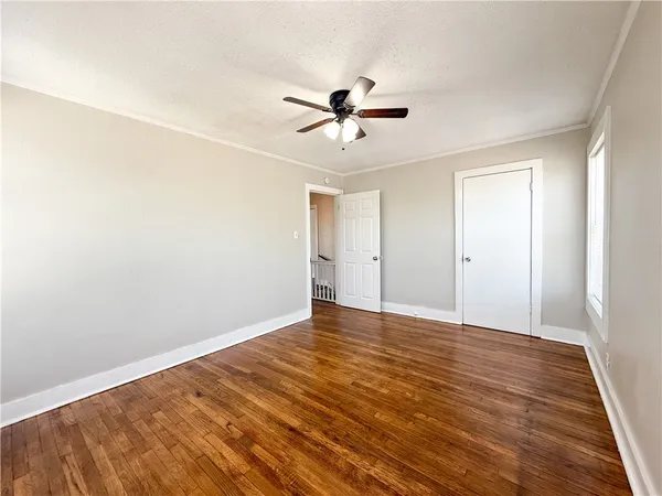 an empty room with wooden floor ceiling fan and windows