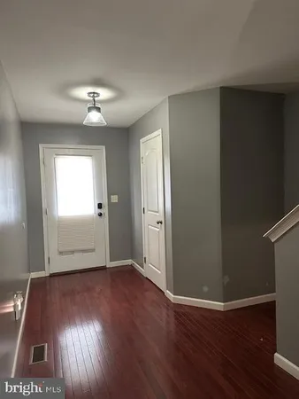 an empty room with wooden floor chandelier fan and windows