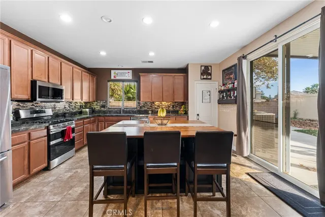 a kitchen with stainless steel appliances granite countertop a stove a sink dishwasher a stove a refrigerator with a dining table and chairs