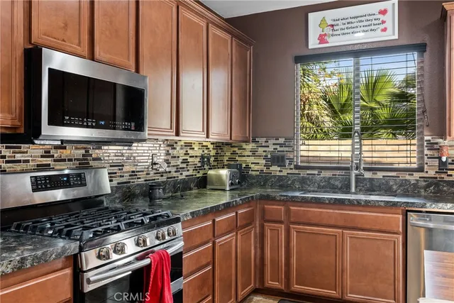 a kitchen with stainless steel appliances wooden cabinets stove and a granite counter top