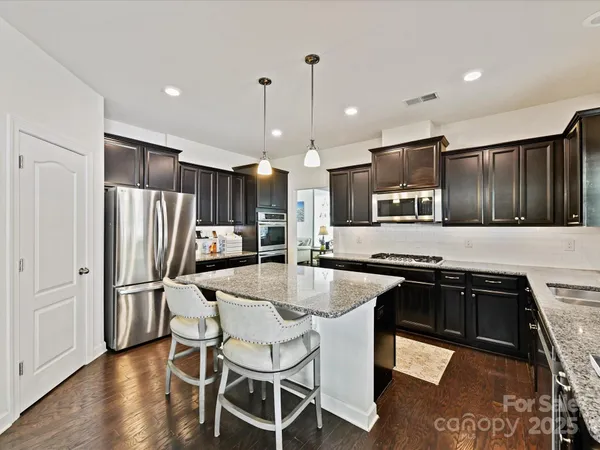 a kitchen with stainless steel appliances granite countertop a stove top oven a sink refrigerator and cabinets