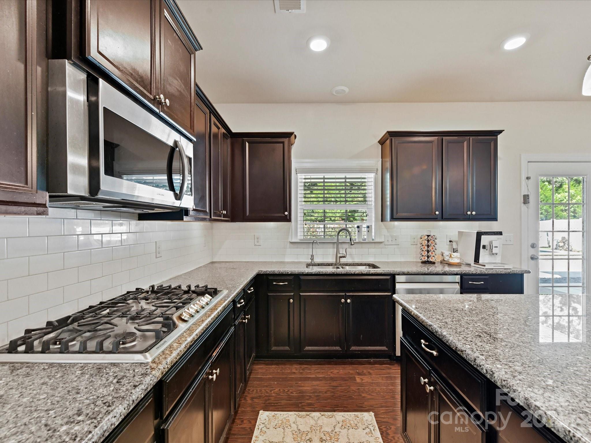 9890 Travertine Trail Davidson, NC 28036 - Photo 13 of 45 a kitchen with stainless steel appliances granite countertop a sink stove and cabinets