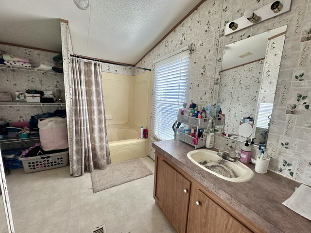 106 Ramirez Street Kyle, TX 78640 - Photo 18 of 19 A compact bath features a tub with shower, a vanity, and integrated storage solutions.
