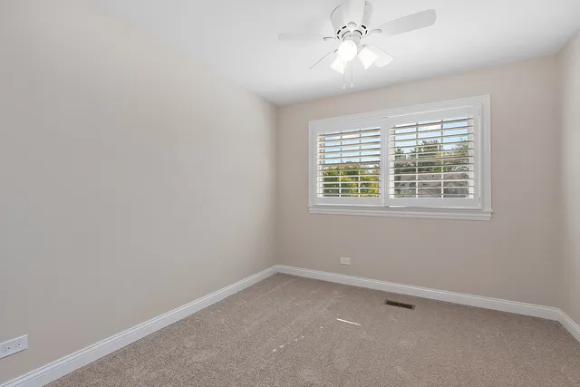 an empty room with a window and a fan