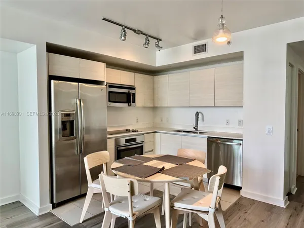 a kitchen with stainless steel appliances granite countertop a stove a refrigerator and a microwave oven with white cabinets