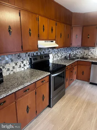 a kitchen with stainless steel appliances granite countertop wooden cabinets a sink and dishwasher
